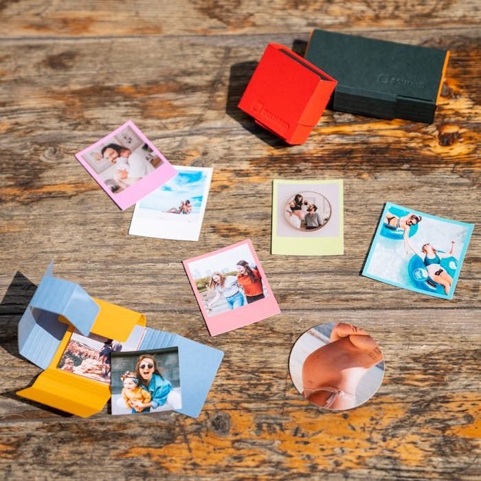Assorted instant photo prints and cases on a wooden table, evoking memories.